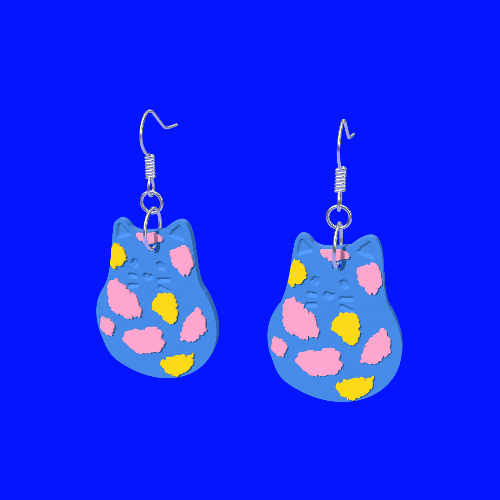 A pair of 40 mm Blue Spotted Cat drop earrings in cobalt blue with pink and yellow spots, worn on ear wires.