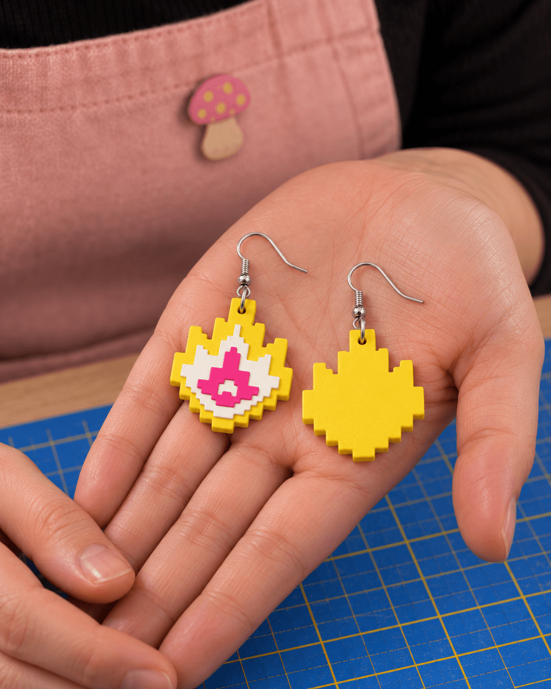 The layered Pixel Flame pair held in a hand, showing its raised front and plain yellow back.