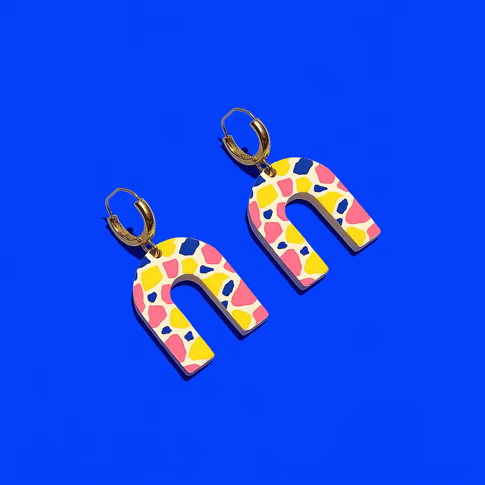 Pair of terrazzo speckled polymer clay arch drop earrings on a white surface