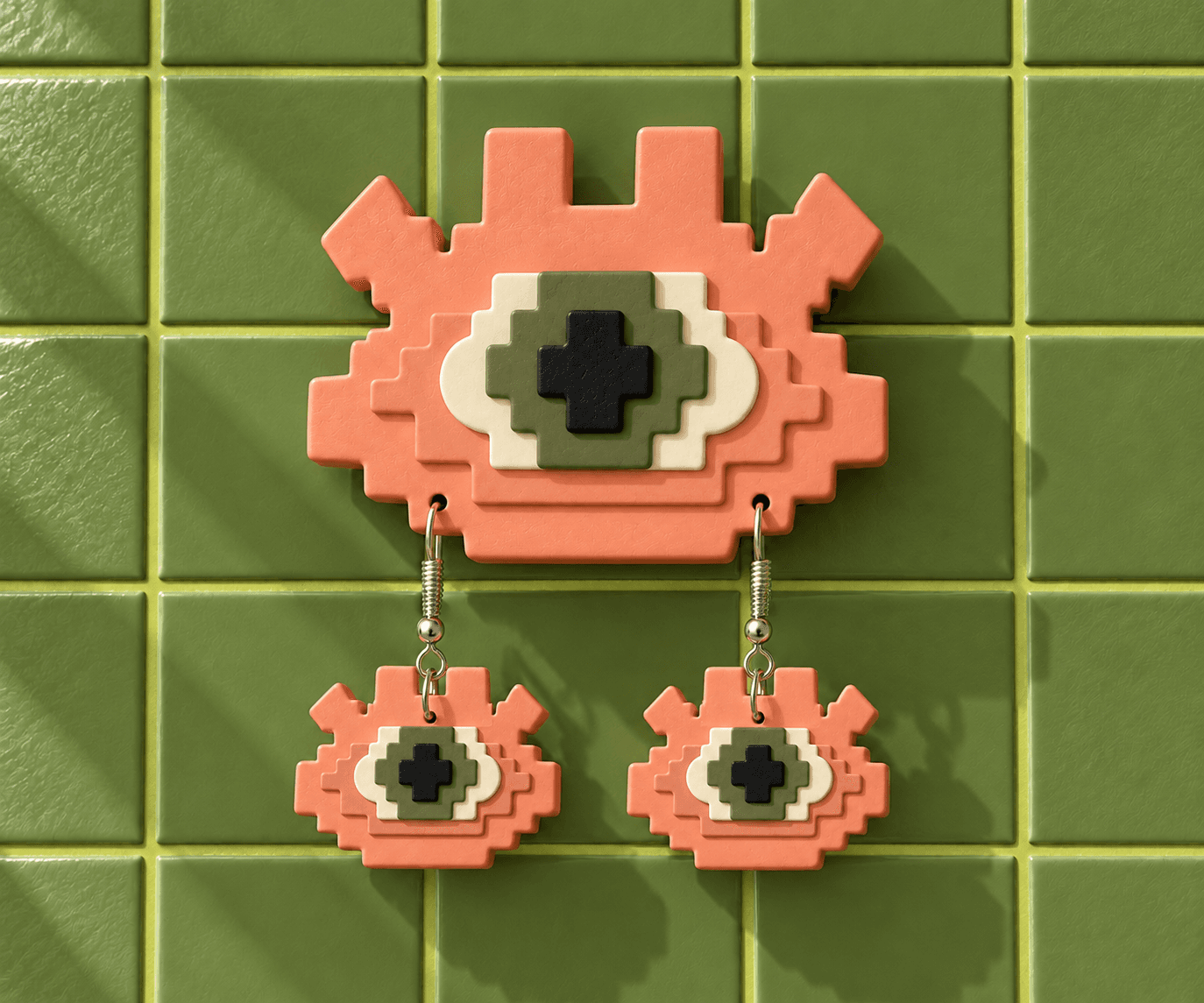 Peach Pixel Eye wall display with an olive iris and matching drop earrings against green tiles.