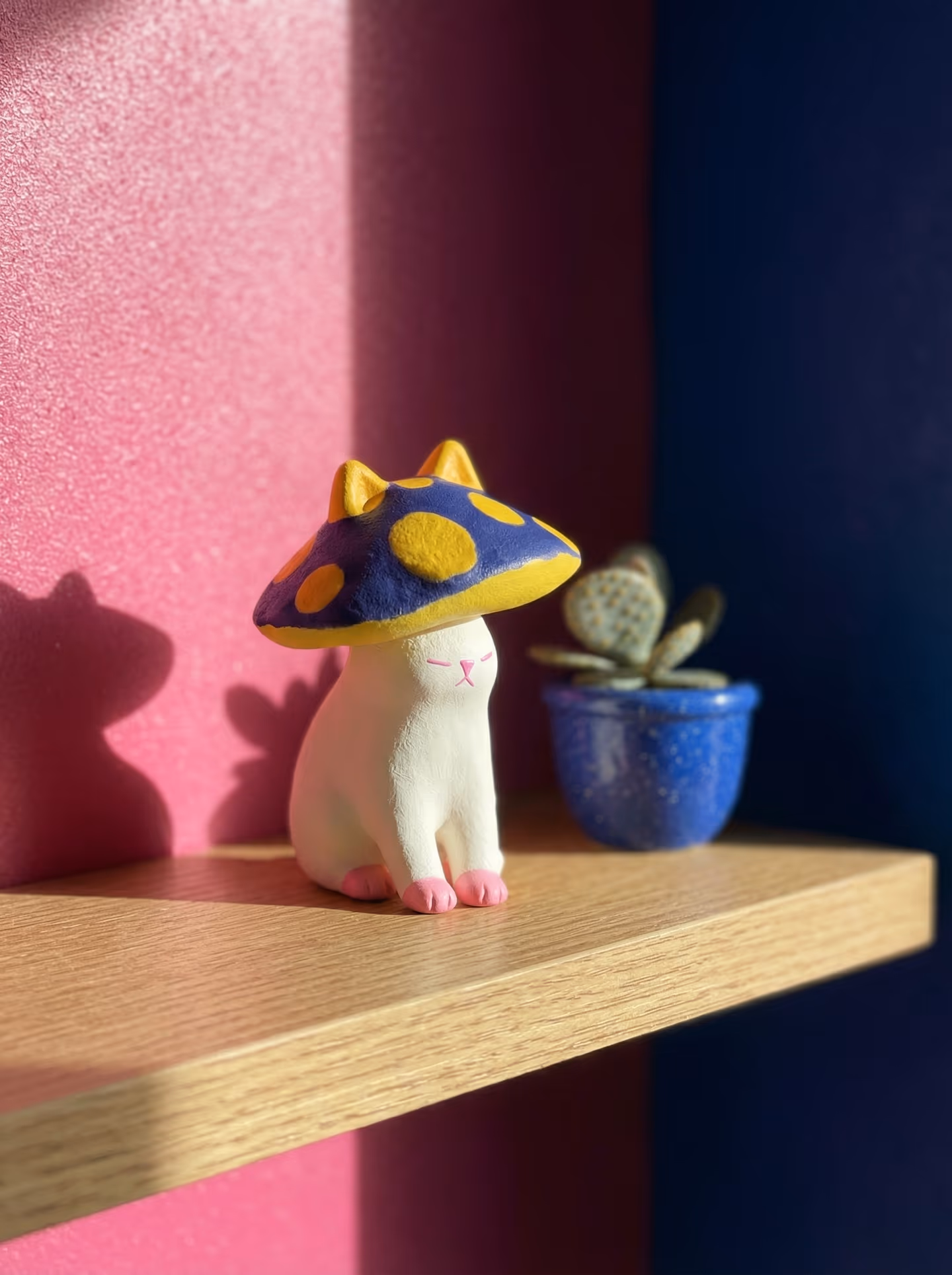 Blue Spotted Mushroom Cap Cat Figurine in styled context. Start with a seated cat body, because the image pair shows a slim stable figure carrying a separate blue cap rather than…