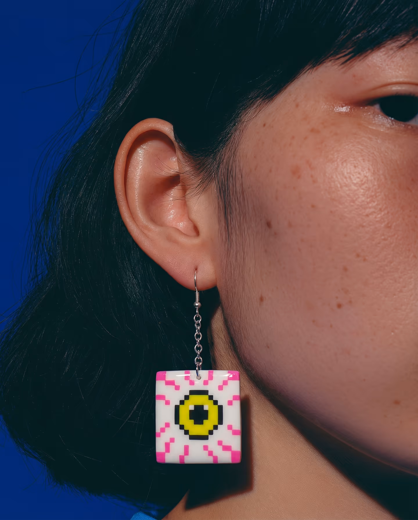 White Pixel Eyeball Tile Earrings in styled context. Start with square white eye tiles and build the iris as layered inserts, because the pair reads as flat plaques with hook-and-…