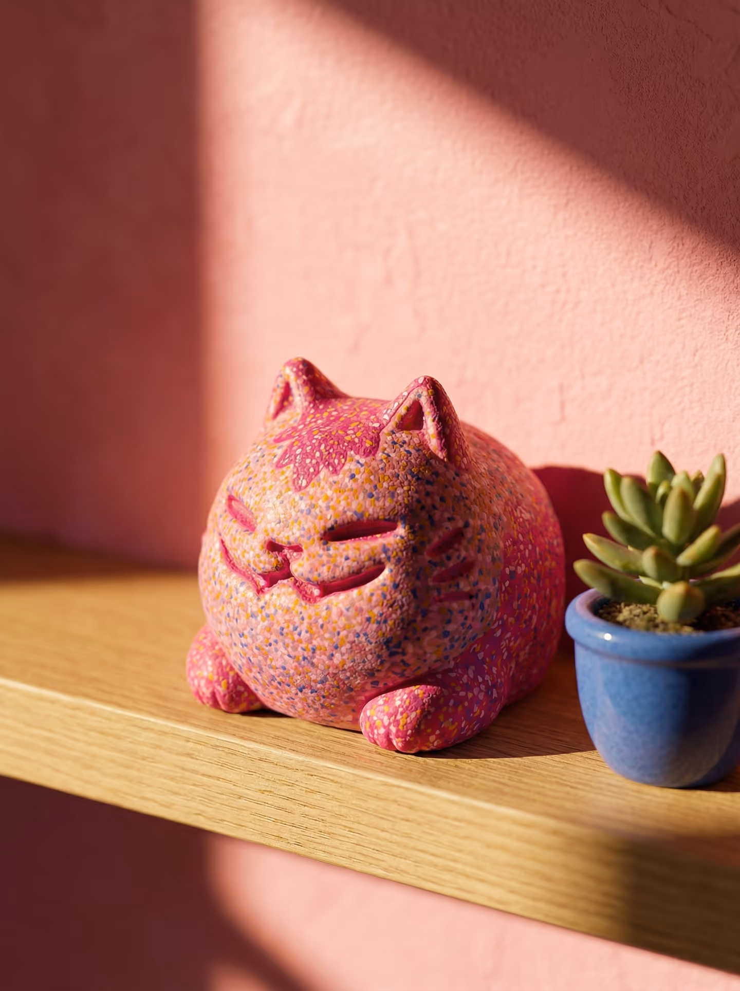 Pink Curled Terrazzo Loaf Cat Figurine in styled context. Start with a compact curled cat sculpt, because the image pair shows one continuous loaf-like body with tucked paws and a…