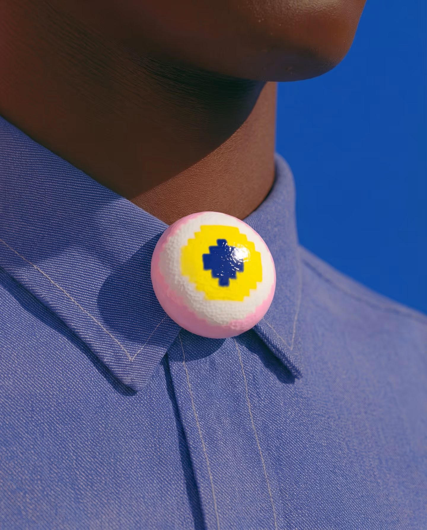 Pink and Yellow Round Pixel Eyeball Brooch in styled context. Build this as a round layered eyeball plaque on one flat pink base, not a full sphere. The product shot shows a sligh…